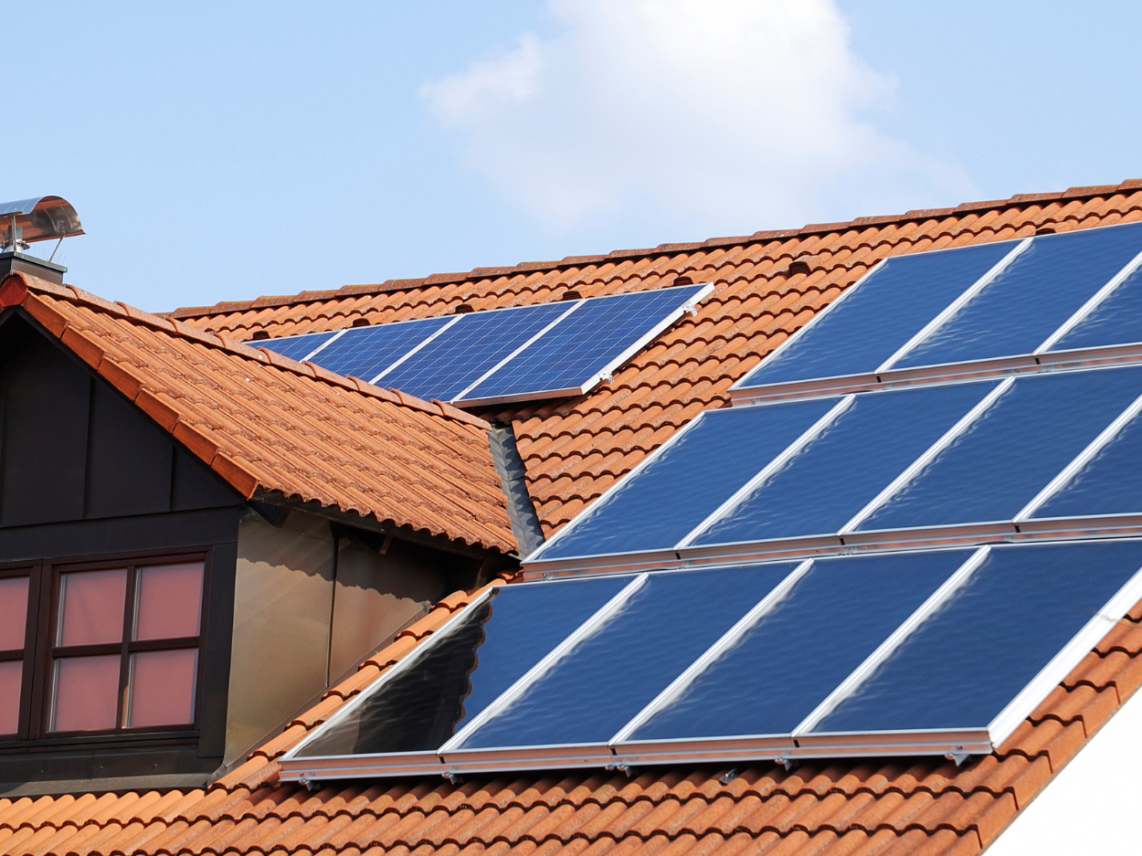 Panneaux solaires sur un toit en tuiles rouges.