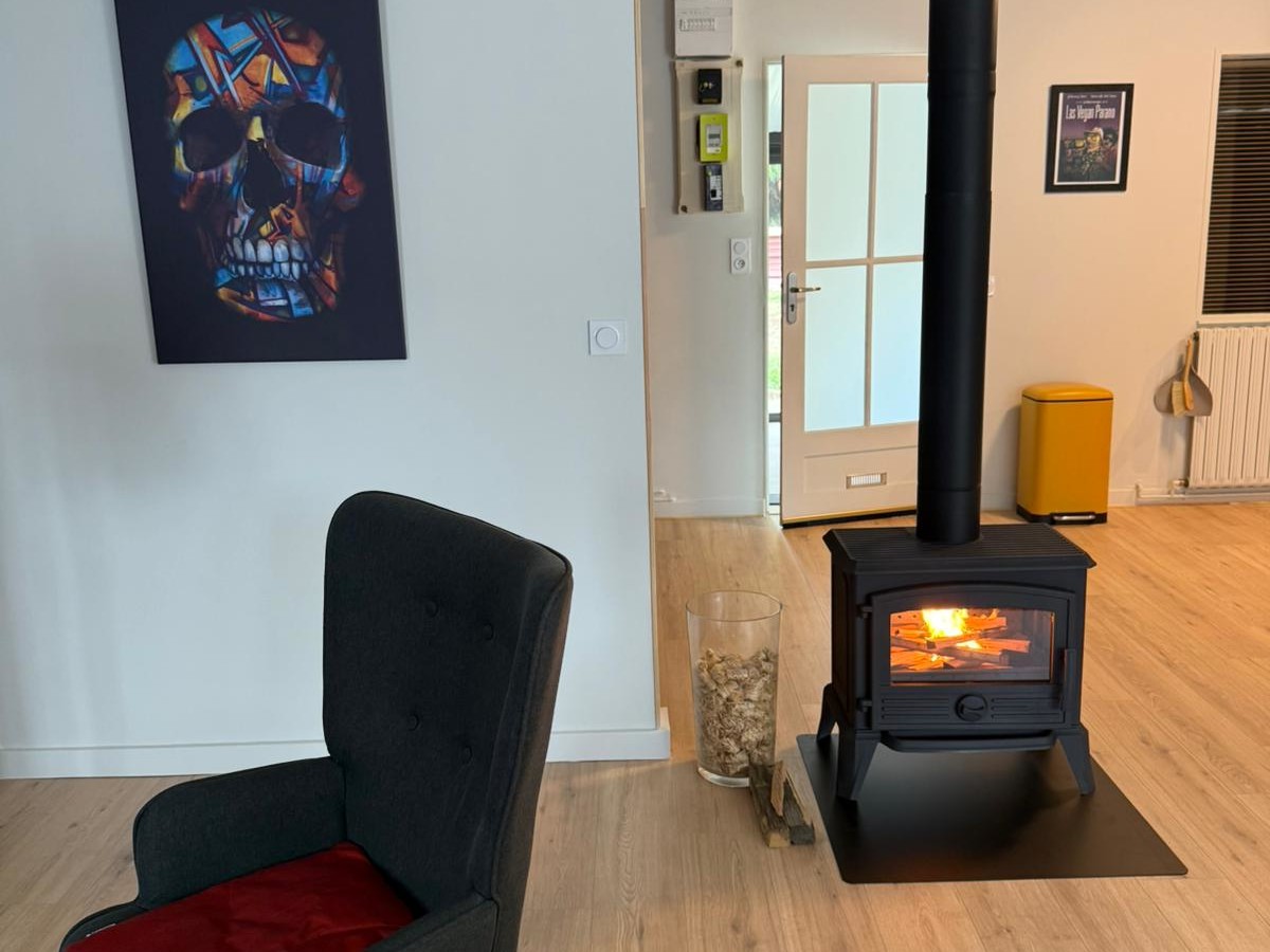Salon avec poêle à bois et fauteuil noir.
